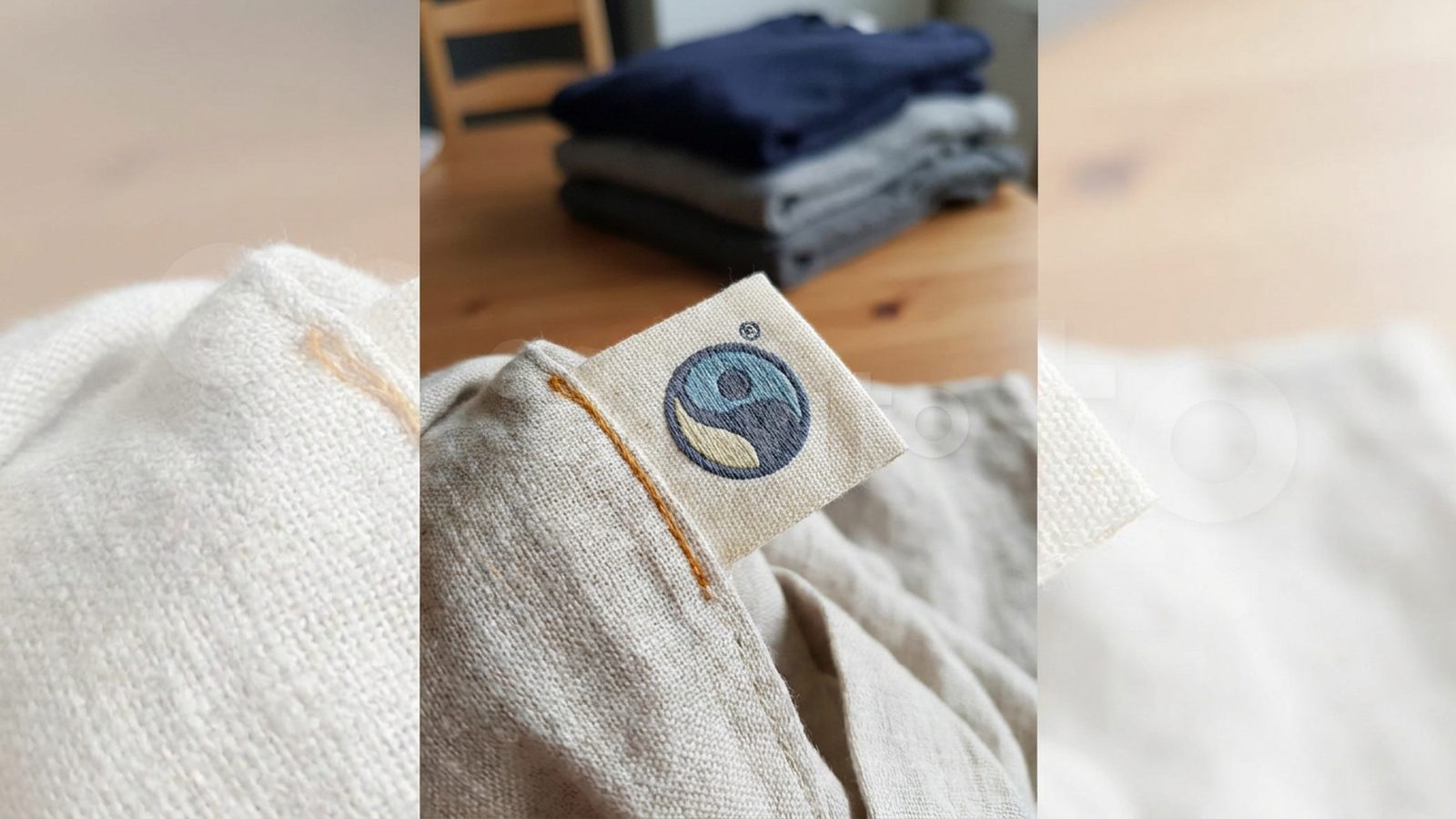 A clothing label with a small Fairtrade symbol is sewn onto undyed linen fabric.
