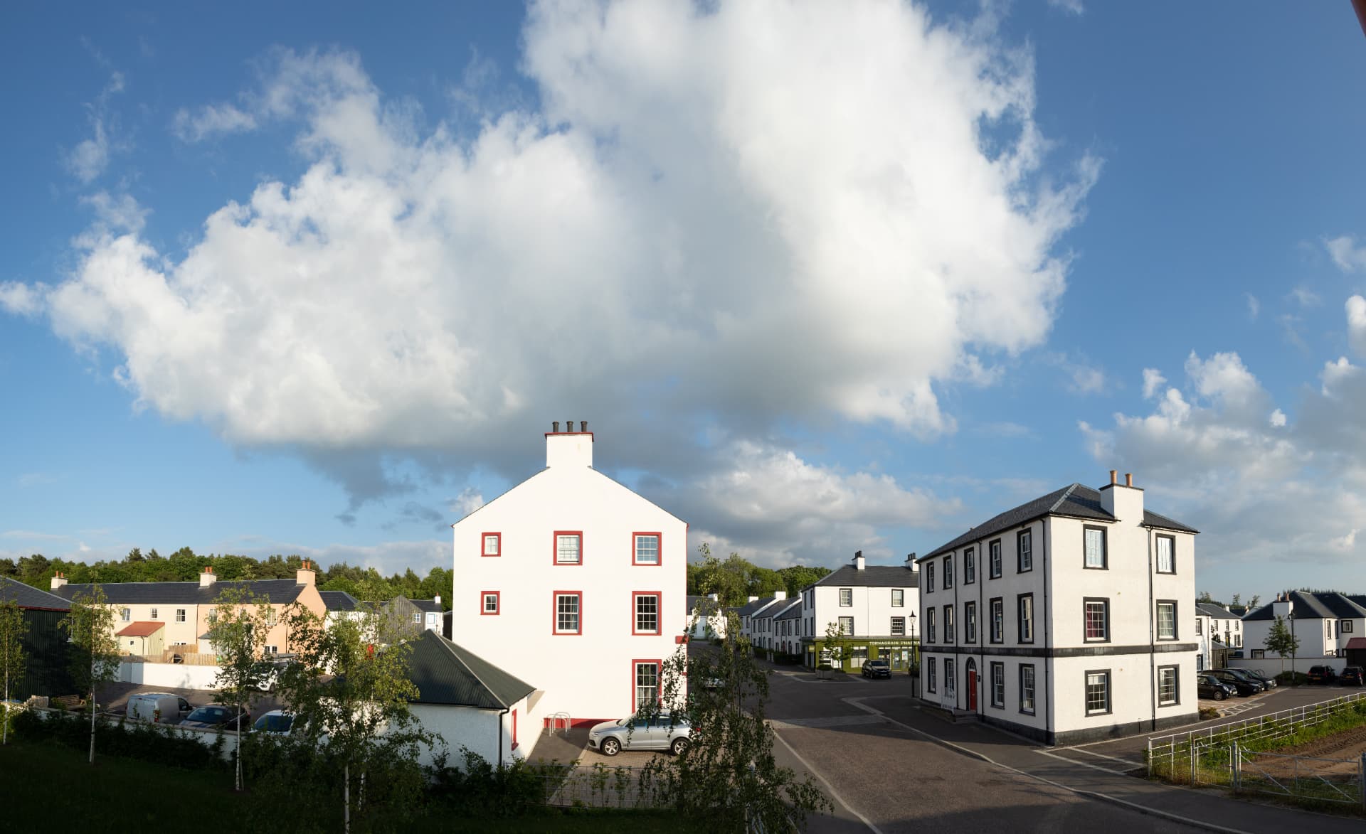 Tornagrain village street in the Scottish Highlands, with white harled houses under a big summer sky